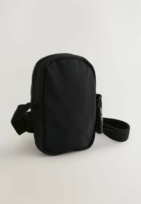 Sort stof crossbody tas med lynlås, rektangulær form og vævet rem. Struktureret overflade uden synlige mønstre eller accenter.