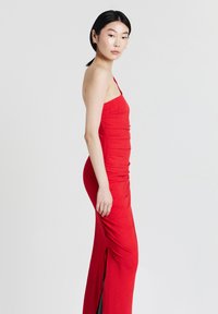 Rotes, figurbetontes Kleid aus strukturierter Stoff, mit einem schulterfreien Design und einem Seiten-Schlitz für zusätzliche Details.
