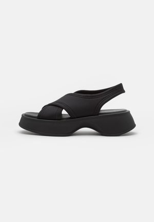 Sorte plateau-sandaler med et slankt design, der har elastiske stropper og en rundet sål for komfort. Teksturerede detaljer langs stropperne.