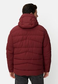 Czerwona pikowana kurtka z wysokim kołnierzem i kapturem. Posiada poziome przeszycia i teksturowane wykończenie. Wykonana z trwałego materiału.