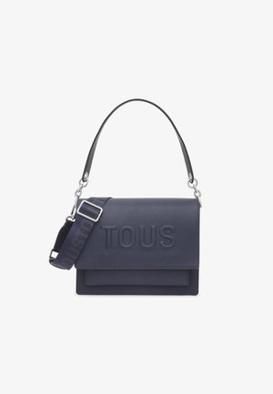 Borsa in pelle blu navy con logo "TOUS" in rilievo, dotata di tracolla removibile con testo, finiture in argento e design strutturato.