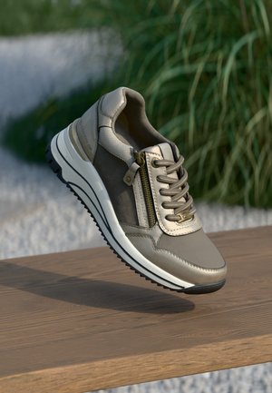 Gaiši pelēki sporta apavi ar teksturētu ādu un audumu, ar sānu rāvējslēdzēju, plakanu auklu un biezām baltām un melnām zolem.