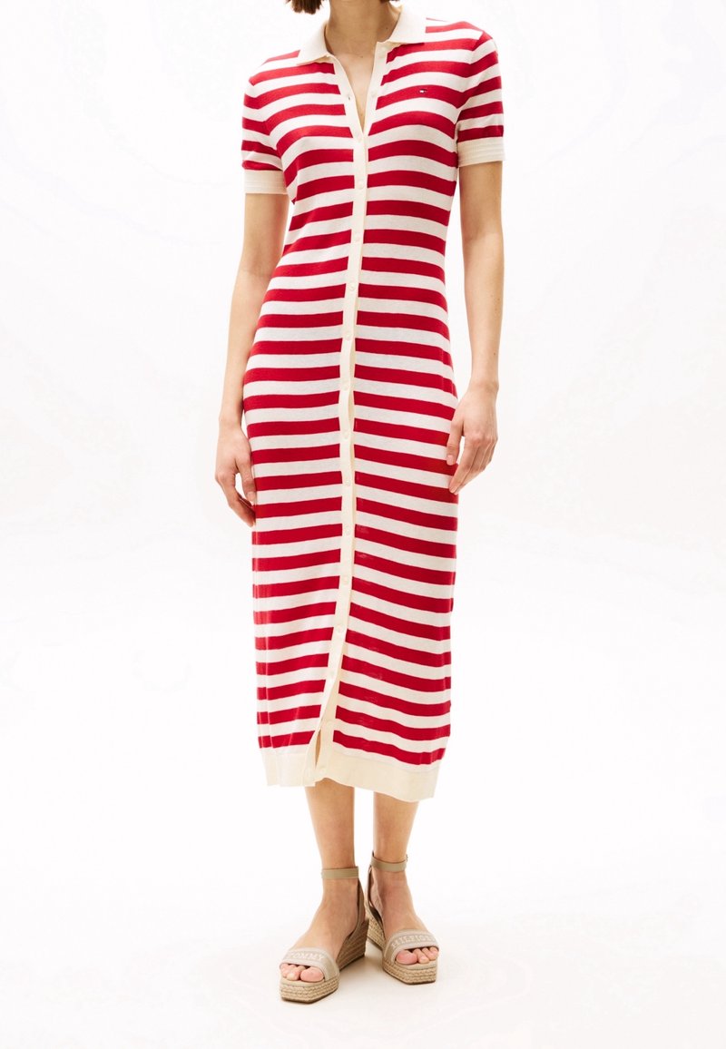 Robe rayée rouge et blanche en tricot avec des manches courtes, un col et des boutons sur le devant, s'étendant jusqu'à mi-mollet, associée à des sandales compensées.