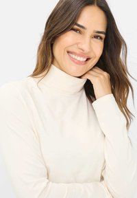 Crèmefarvet turtleneck lavet af blødt stof, med lange ærmer og tætsiddende design. Glat tekstur med høj krave.