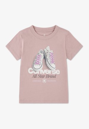 Svetloružové tričko s krátkym rukávom s grafikou sivých tenisiek s ružovými šnúrkami a textom "Converse All Star Brand" na prednej strane.