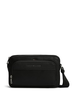 Sac bandoulière en cuir noir texturé avec poche avant zippée et sangle réglable, marqué du logo Tommy Hilfiger en lettres argentées.
