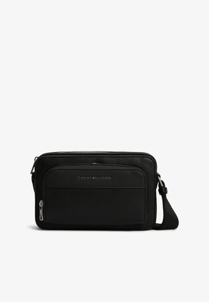 Czarna, teksturowana skórzana torba na ramię z przednią kieszenią na suwak i regulowanym paskiem, oznakowana srebrnym logo Tommy Hilfiger.