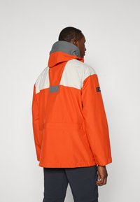 Bright orange waterproof jacket with a gray hood, white shoulder panels, adjustable cuffs, and a back pocket detail.