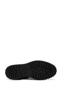 Suela de bota de goma negra con un patrón de textura y surcos profundos y acentos circulares para mayor tracción. Diseño plano y duradero.