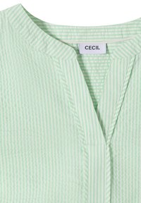 Chemise rayée verticalement vert clair et blanc avec un col mao et un col en V ouvert.