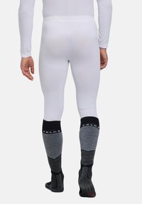 Sous-vêtement à manches longues blanc associé à des chaussettes jusqu'aux genoux grises et noires avec un design côtelé et une semelle texturée pour une meilleure adhérence.