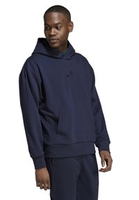 Felpa con cappuccio color blu navy realizzata in tessuto morbido, dotata di tasca a marsupio e piccolo logo sul petto. Presenta un cappuccio con cordino e polsini a coste.