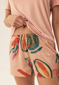 Jasnoróżowa koszula i szorty w wzory z abstrakcyjnymi, kolorowymi motywami w odcieniach pomarańczowym, zielonym i niebieskim, z elastycznym pasem.