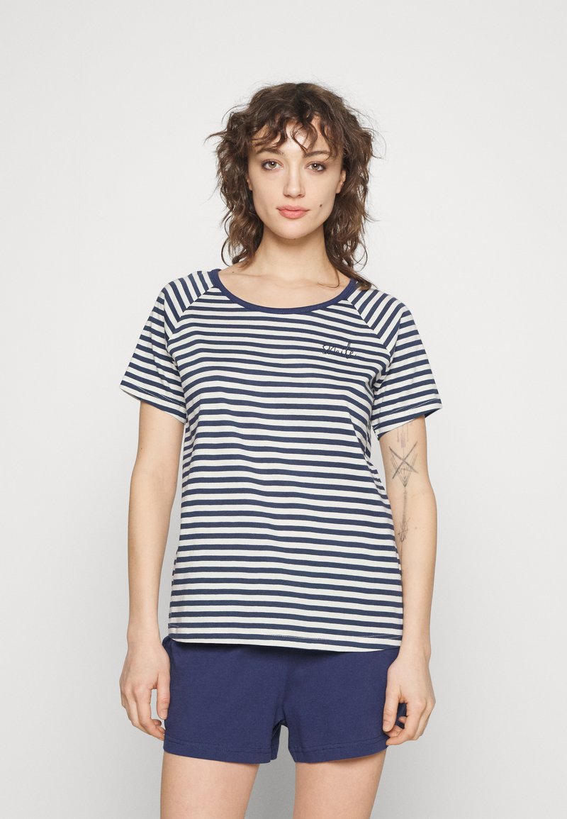 Camiseta a rayas en azul marino y crema con cuello redondo y mangas cortas, combinada con pantalones cortos azul marino; ajuste relajado y tela suave.