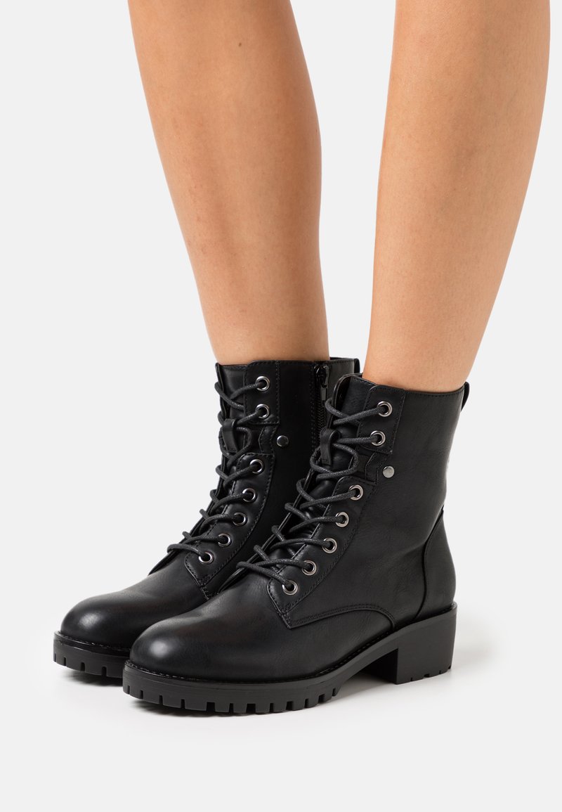 Botas de cuero negro hasta el tobillo con cordones y ojales de metal, acabado texturizado, tacón cuadrado, cremallera lateral, suela de goma duradera y sin patrones visibles.