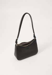 Sac en cuir noir avec zip doré, bandoulière unique et petit logo en relief à l'avant sur fond blanc.