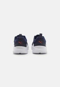 Scarpe sportive in rete blu navy con suole bianche, dotate di un logo rosso sul tallone e linguette per una facile calzata. Parte superiore testurizzata per traspirabilità.