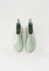Bottes de pluie en caoutchouc vertes avec une finition brillante, hauteur cheville, with tirants et une semelle intérieure rembourrée. L'intérieur est bleu clair.