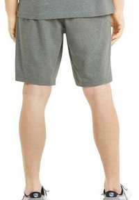 Grå bomuldsblandede træningsshorts, knæ-lange, med et elastisk bånd i taljen og en blød tekstur. Båret med grå sneakers.