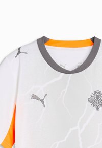 Maillot de sport blanc avec col gris, encolure intérieure orange, logo Puma sur la poitrine et l'épaule, et un emblème stylisé sur le côté droit de la poitrine.