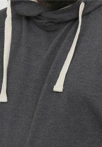 Sudadera gris oscuro con cordones y detalles en crema. El material parece suave, con una ligera textura, mostrando un diseño casual.