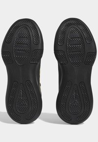 Sole di scarpe sportive nere con battistrada a motivo, caratterizzate da un design a onda per la presa. I materiali includono gomma; texture liscia con accenti rialzati.