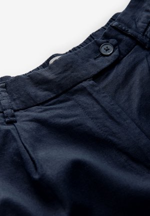 Marinblå byxor med platt midjeband, knappstängning och texturerat tyg. Har synliga sömmar och en slät yta.