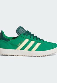 Green suede sneakers with white three-stripe design and "Gazelle" branding. Features rubber outsole, textured details, and padded tongue.