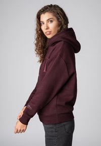Bordeaux hoodie met een relaxed fit, voorzien van een textuur en ribbels aan de mouwen. Subtiele logodetail op de mouw.