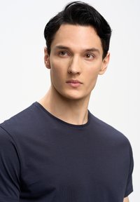 T-shirt blu navy a maniche corte realizzato in tessuto liscio, con colletto a girocollo, taglio aderente e senza motivi o dettagli visibili.
