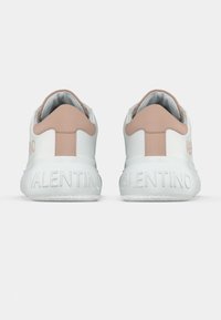 Biele tenisky s jemnými ružovými akcentmi. Majú hladký kožený povrch, polstrovaný jazyk a vytlačené logo na päte.