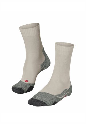 Calzini beige con trama a costine, con punta e tallone grigi e un logo rosso nella parte inferiore. Design a metà polpaccio.