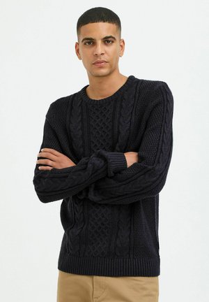 Dark navy sweater featuring a textured cable knit pattern, ribbed cuffs and hem, and a classic crew neckline. Material appears thick and warm.