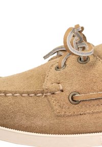 Beige mokasyn z zamszu z okrągłym noskiem, skórzanymi sznurowadłami, metalowymi oczkami i białą gumową podeszwą z widocznymi detalami szwu.