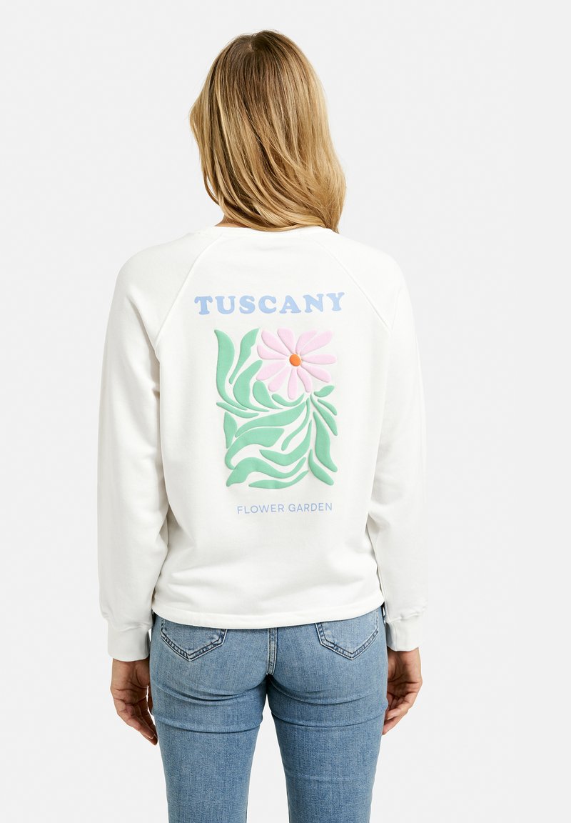 White sweatshirt with a colorful floral design featuring a pink flower, green leaves, and the text "TUSCANY FLOWER GARDEN" on the back.