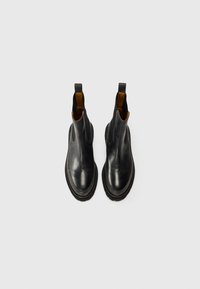 Bottines noires en cuir avec semelle en caoutchouc, finition lisse, côtés élastiques et accents intérieurs beiges. Caractéristiques de languettes pour un enfilage facile.