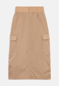 Jupe beige mi-longue en tissu léger. Elle présente une taille élastique et deux poches latérales pour le rangement.