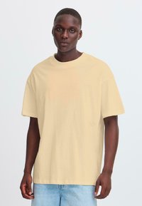 Losse, kortlopende t-shirt in lichtgeel, gemaakt van zachte katoen. Heeft een ronde halslijn en een subtiel logo-detail op de onderkant van de voorkant.