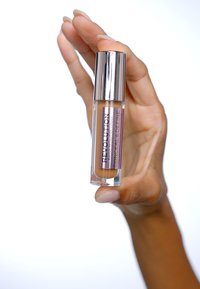 Correcteur Makeup Revolution dans un tube transparent avec un capuchon argenté ; contient un produit orange ; l'étiquette indique "Conceal & Define."