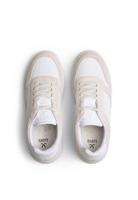 Baskets beige et blanches avec une tige en cuir lisse et des accents en daim, un design de bout perforé et des lacets plats. Semelle extérieure en caoutchouc.