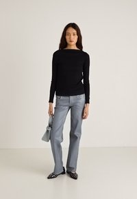 Juoda ilgomis rankovėmis palaidinė, šviesiai mėlyni aukštos liemens džinsai, deranti pilka rankinė ir juodi bateliai su smailiais priekiu bei baltais akcentais.