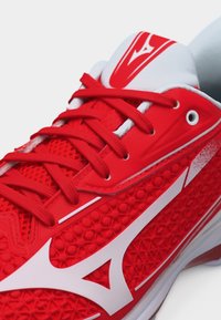 Punainen urheilukenkä, jossa on kuvioitu pinta, punaiset nauhat, valkoinen logo sivulla ja valkoinen pehmustettu kieli, jossa punainen logo.