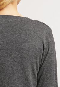 Dunkelgrauer Strickpullover mit rundem Ausschnitt, zeigt Textur und eine glatte Oberfläche. Die Rückseite ist schlicht und ungeschmückt gestaltet.