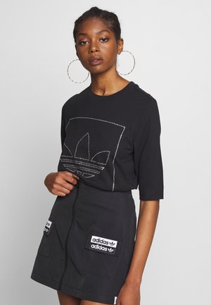 T-shirt nera in cotone con grafica di strass, abbinata a una gonna nera con zip che presenta due tasche frontali e toppe con marchio.