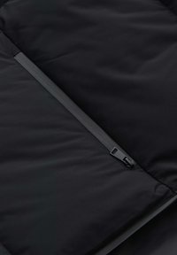 Schwarzer, isolierter Jackenstoff mit glatter Textur, der einen verdeckten Reißverschluss und ein minimalistisches Design aufweist.