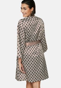 Gemusterd gewaad met een diamanten patroon in perzik en zwart, lichte stof, ceintuur in de taille en driekwart mouwen.