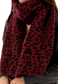 Sciarpa con stampa leopardata rossa e nera realizzata in tessuto morbido, caratterizzata da un design ampio che si avvolge attorno al collo e pende in modo sciolto.