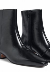 Melnas ādas potītes zābaki ar smailu purngalu, ar rāvējslēdzēju vienā pusē un zemu papēdi. Gluda tekstūra ar spīdīgu apdari.