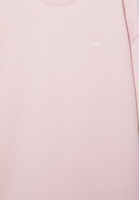 Jasnoróżowa bluza z okrągłym dekoltem z małym białym haftowanym napisem "SikSilk" na lewej piersi.