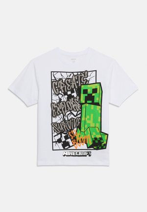 Λευκό μπλουζάκι με εικόνα Minecraft Creeper, μαύρο γκράφιτι κείμενο "Δημιούργησε Εξερεύνησε Επιβίωσε," και πορτοκαλί "sss.. Μπουμ" σε φόντο σπασμένου μπλοκ.